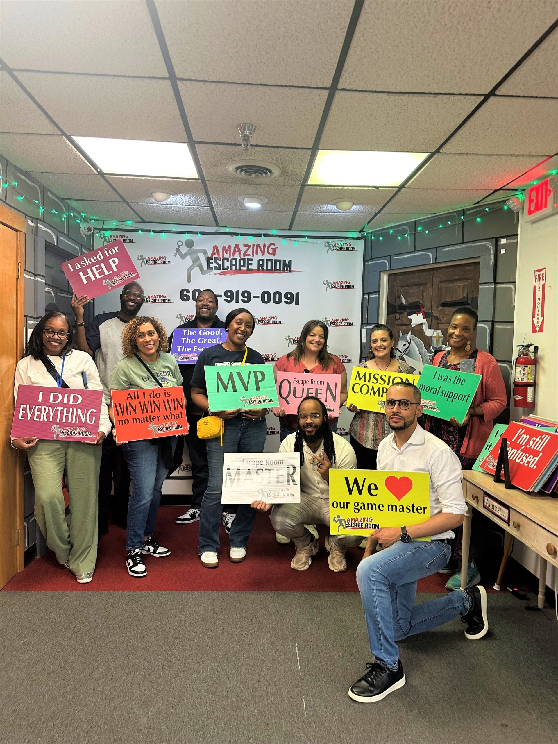 A group of people holding signs at an escape room game center. 