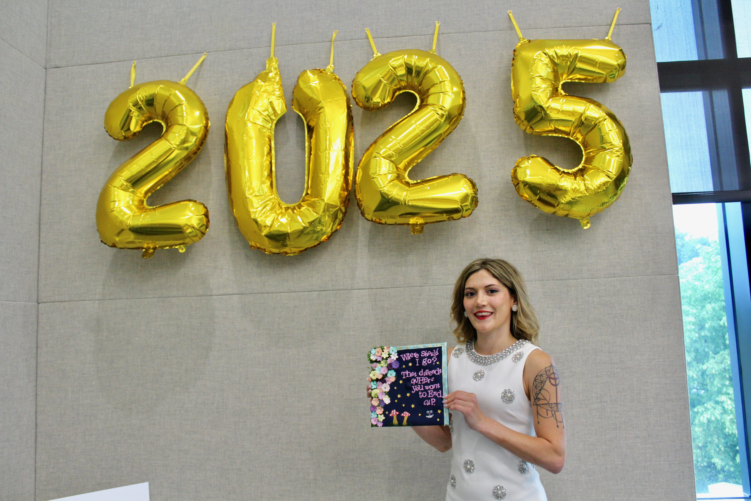 Student posing with graduation cap in front of balloons