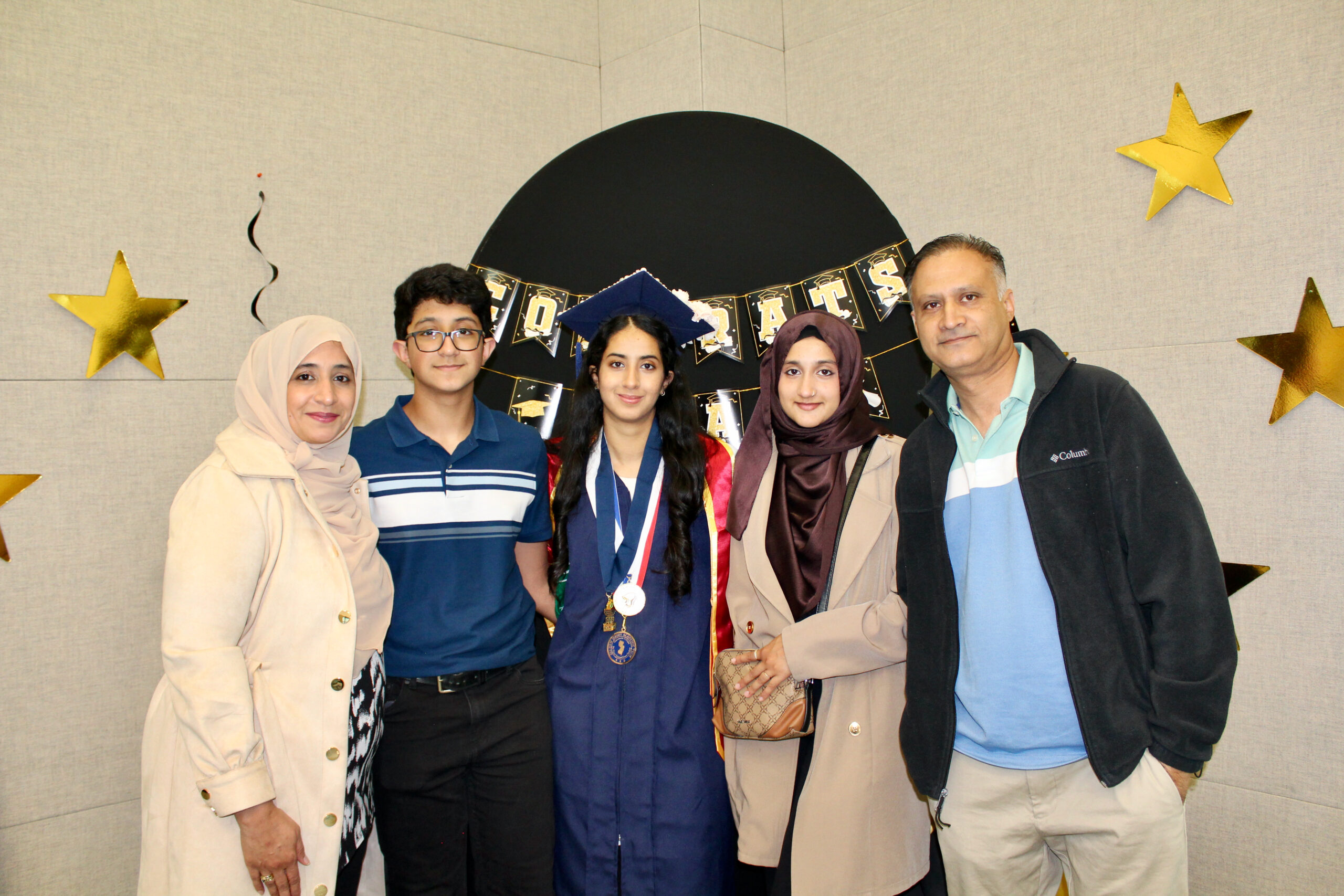 student in cap & gown posing with her family 