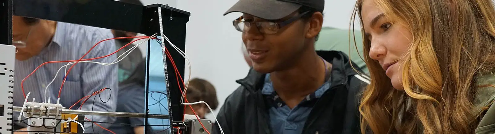 Students working together using electrical equipment with professor