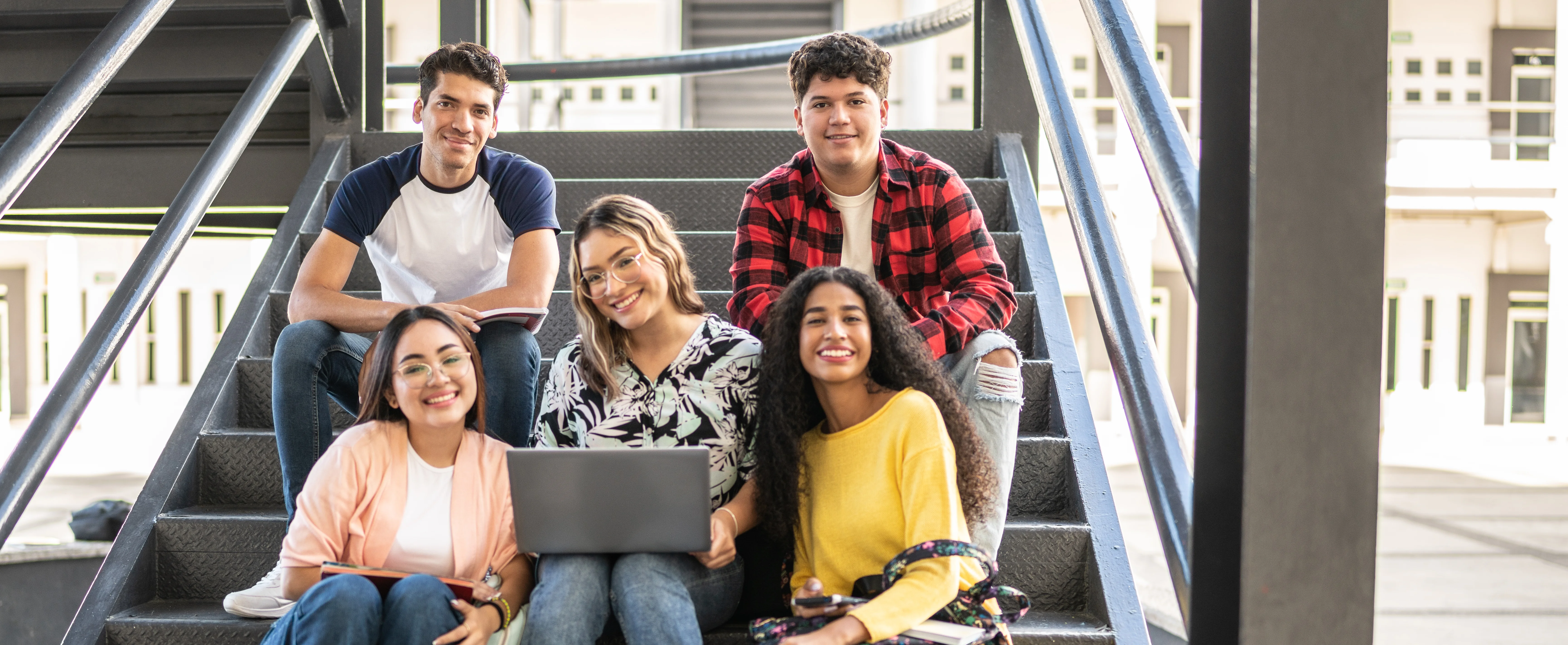 students sitting on steps with a laptop